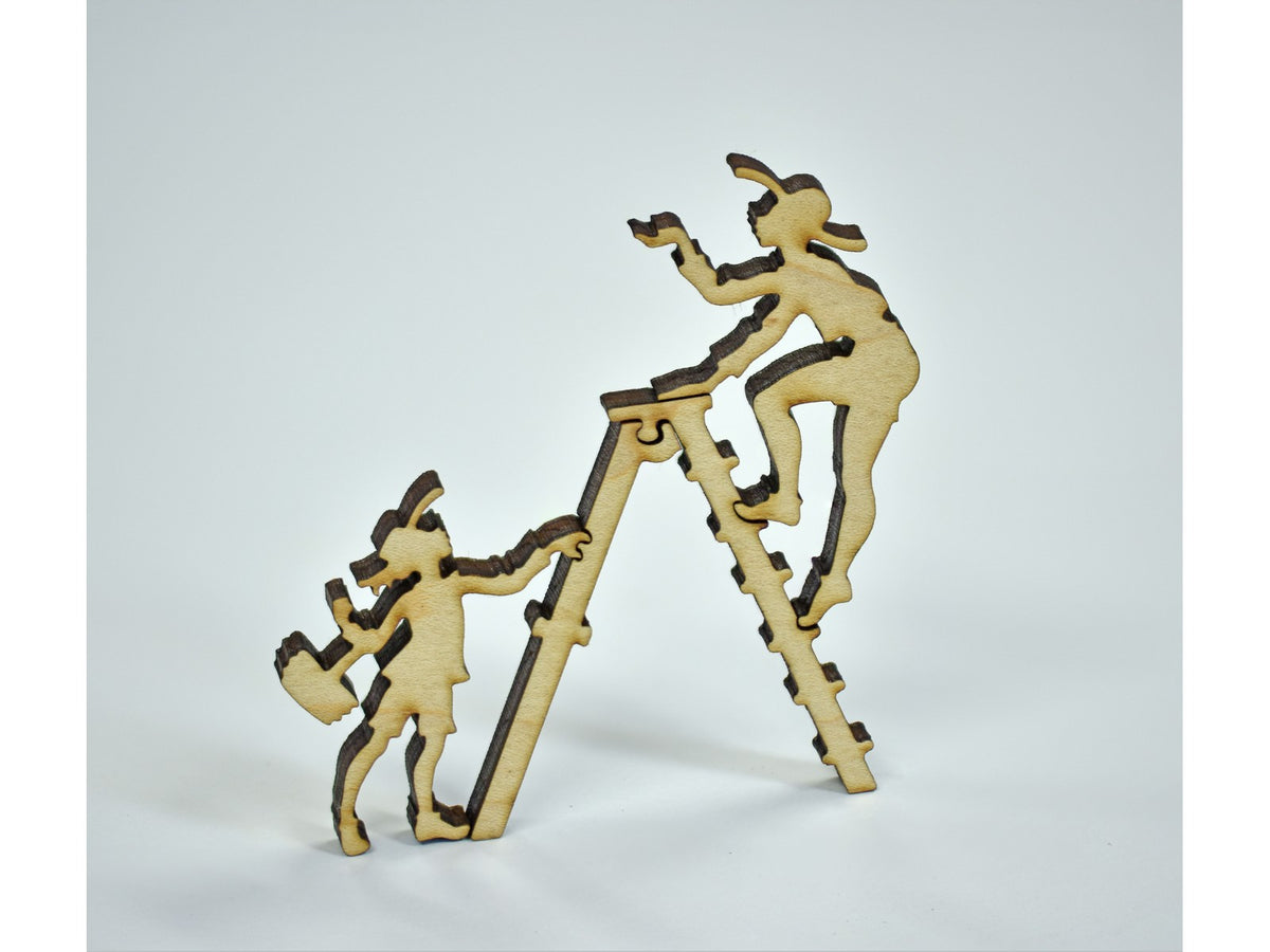 A closeup of pieces in the shape of people picking fruit on a ladder.