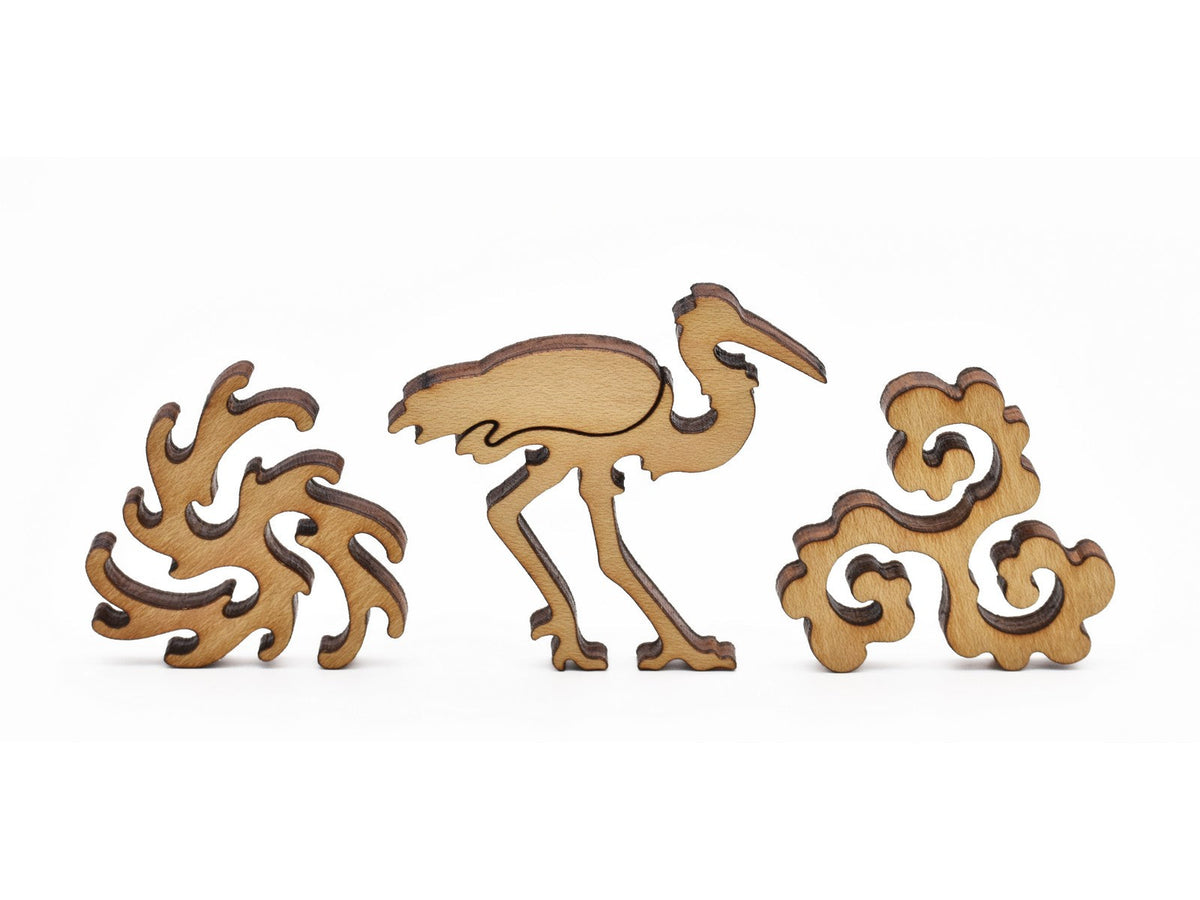 A closeup of pieces in the shape of a crane and water swirls.