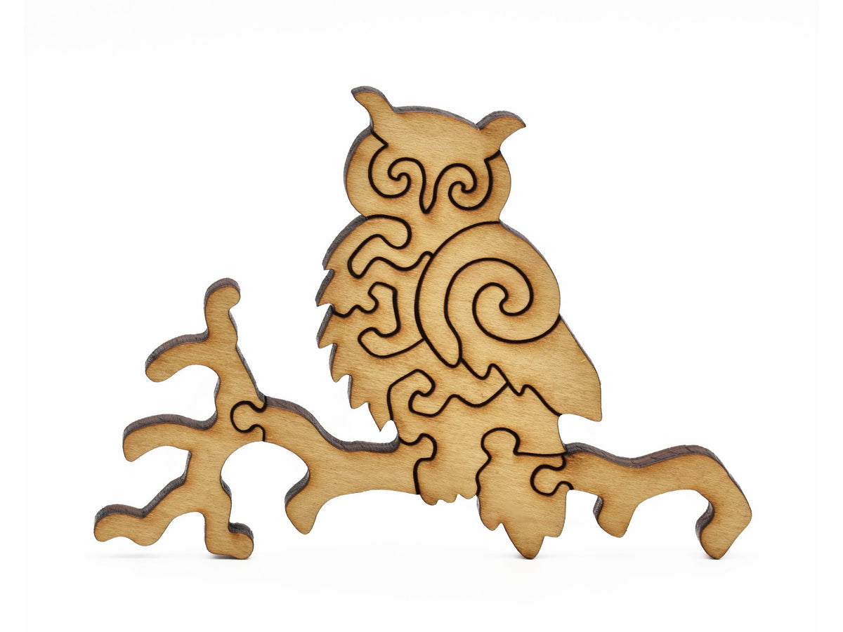 A closeup of pieces in the shape of an owl perched on a branch. 