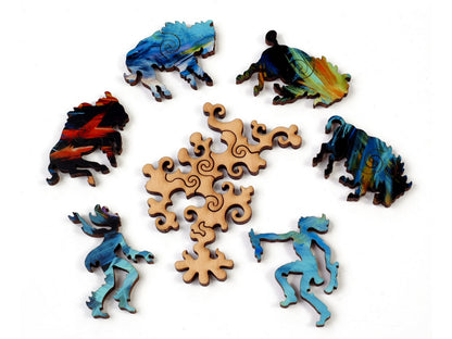 A closeup of some pieces in the shape of four bison, and two people dancing around a fire.