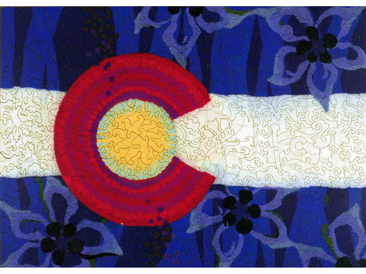 The front of the puzzle, Colorado Flag LG, picturing an artistic rendering of the Colorado flag in felted wool, with aspen tree trunks and columbine flowers.